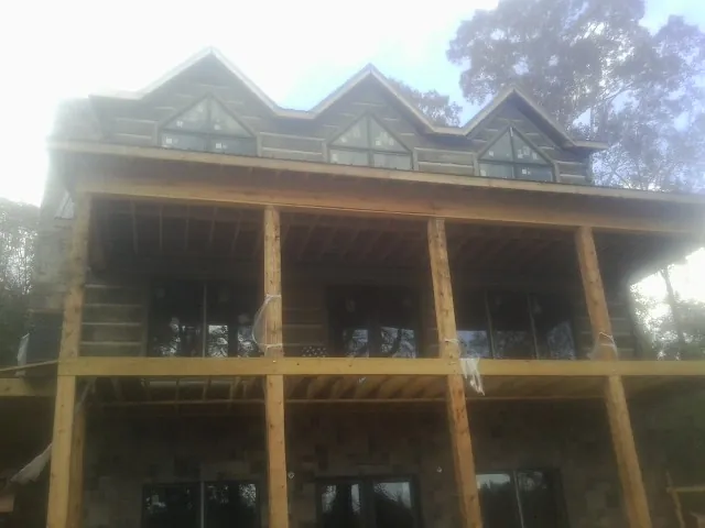 Dormers and porch framing on a large log home under construction — Roof Coating work by our crew in Gilbertsville