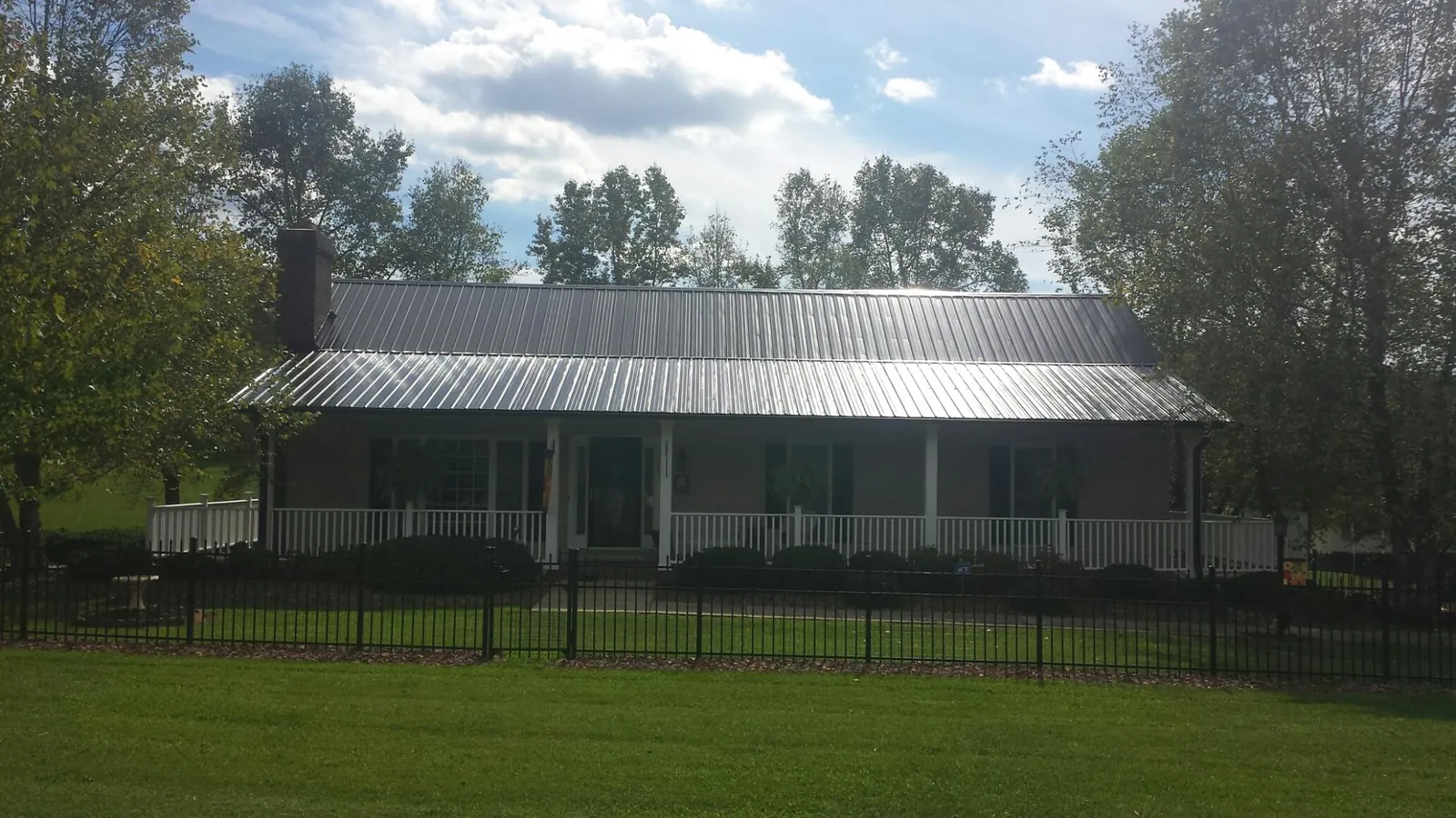 Gray metal roof on a brick ranch with a full width front porch — Gutter Guard Installation work by our crew in Gilbertsville