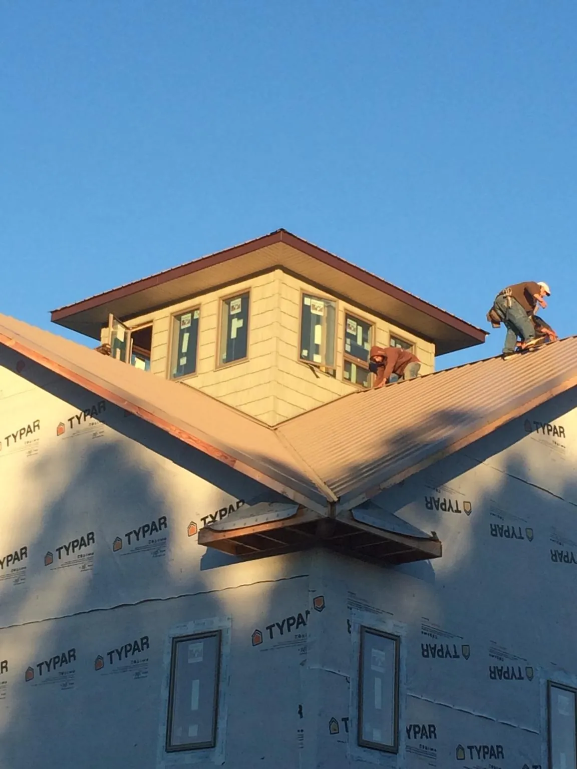 Roofers working around a rooftop cupola on a new metal roof at sunset — Roof Waterproofing in Gilbertsville by Roofing Brothers